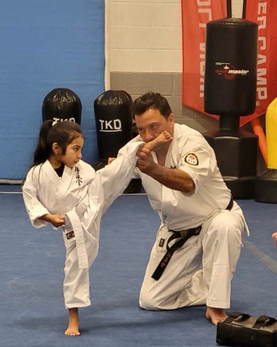 US Bushido instructor guiding kids karate kicks in Gaithersburg MD
